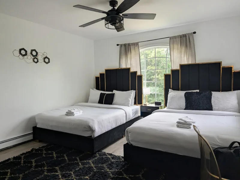 A finished New York bedroom with neatly made beds and polished wood floors.